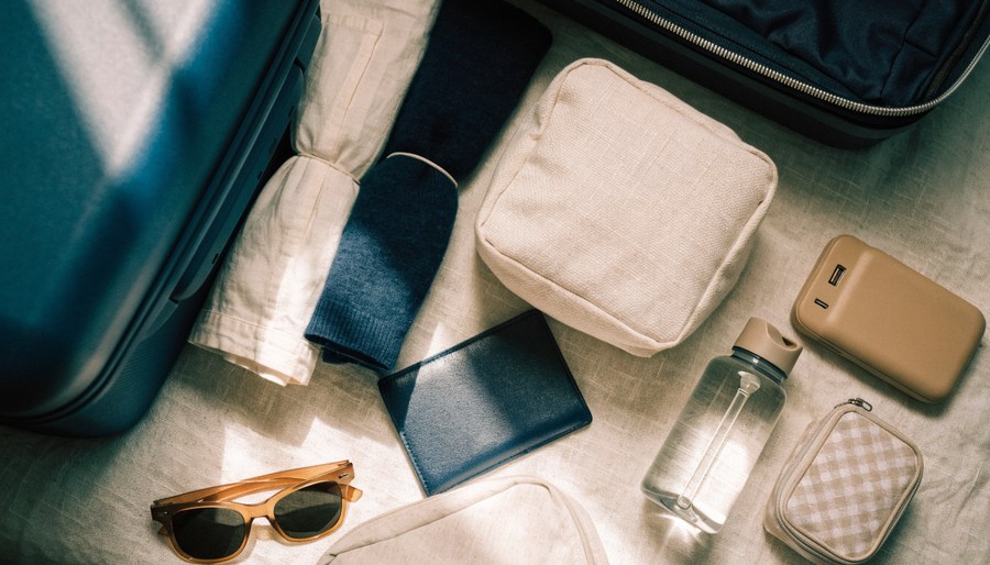 Travel packing essentials laid out on a linen surface
